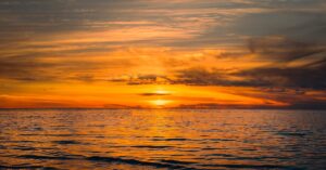 Stunning golden sunset over a calm ocean, capturing nature's serene beauty and vibrant horizons.
